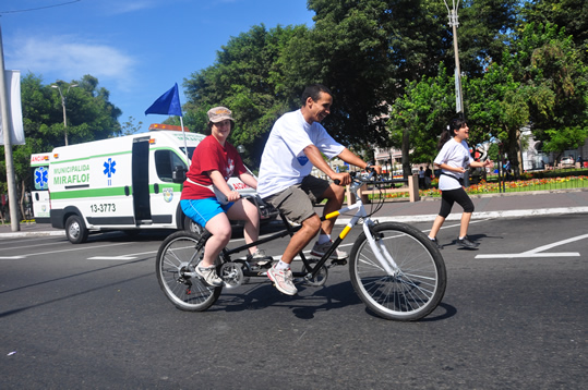 Joven con Síndrome Down disfruta de un paseo inclusivo en bici por el parque Kennedy, gracias al voluntariado municipal.